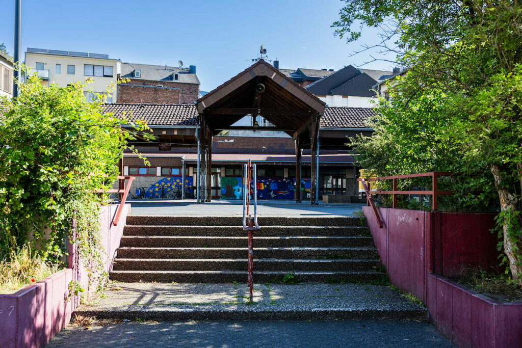 Eingang zum Schulhof. Eine Treppe führt auf den Schulhof nach oben