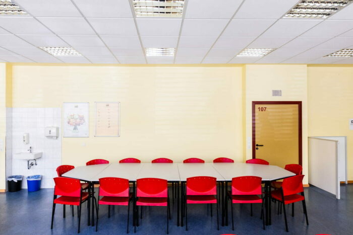 Großer Esstisch mit roten Stühlen in der Kantine