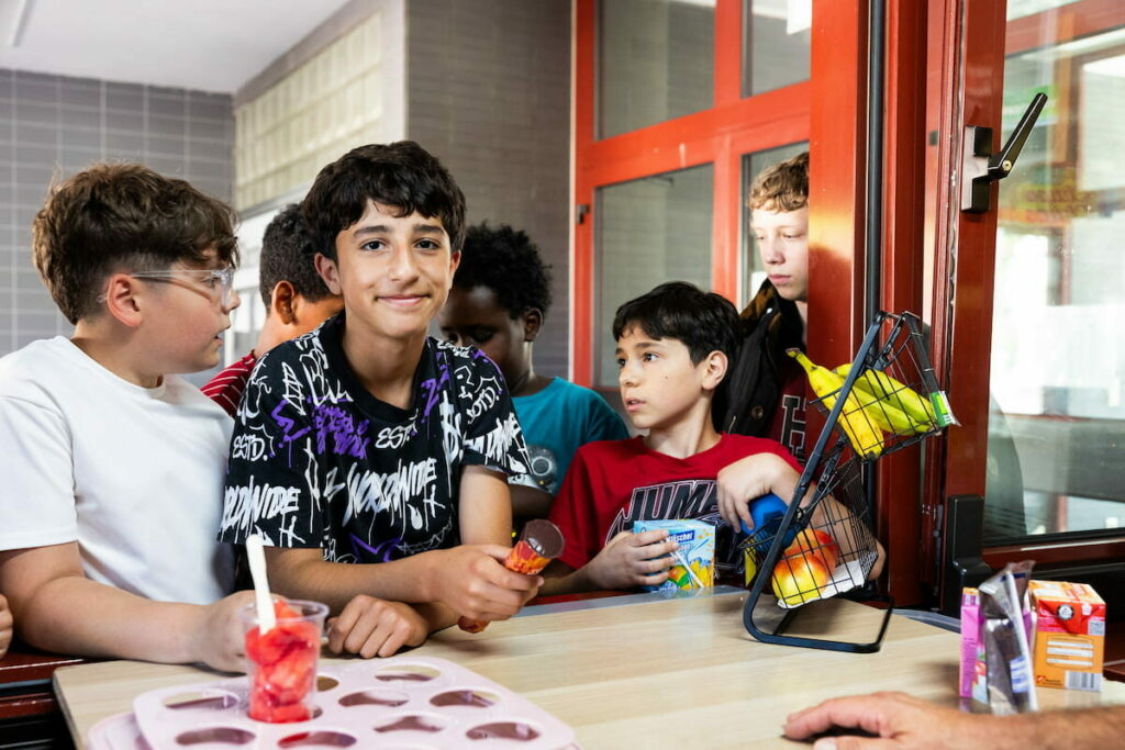 Kinder stehen am Kiosk an, um sich mit Snacks oder Getränken einzudecken