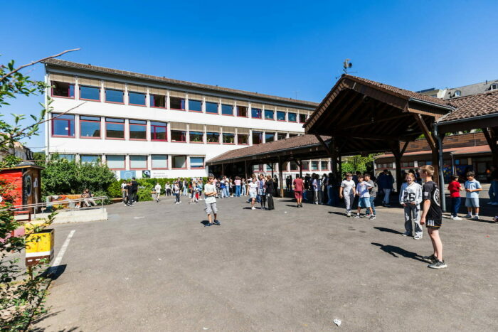 Die Schülerinnen und Schüler genießen die Pause auf dem sonnigen Schulhof